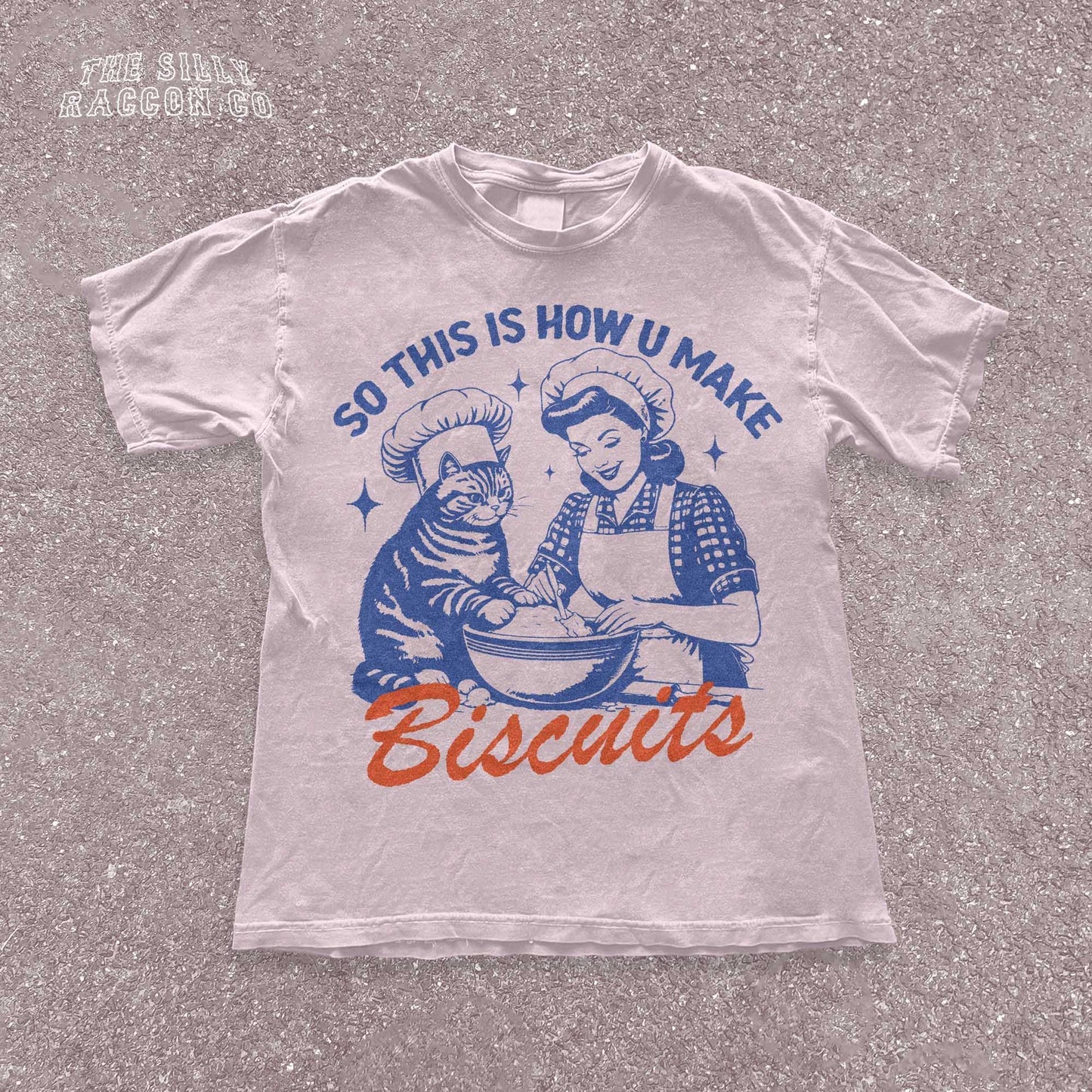 Funny cat t-shirt for men and women featuring a vintage-style illustration of a woman and a cat "making biscuits" together in a mixing bowl. The cat wears a chef hat, humorously mimicking the kneading behavior cats are known for. Retro colors and design give it a nostalgic feel. Great for cat lovers, pet parents, and fans of funny animal shirts. Makes a perfect gift for cat moms, dads, or kitchen humor enthusiasts.