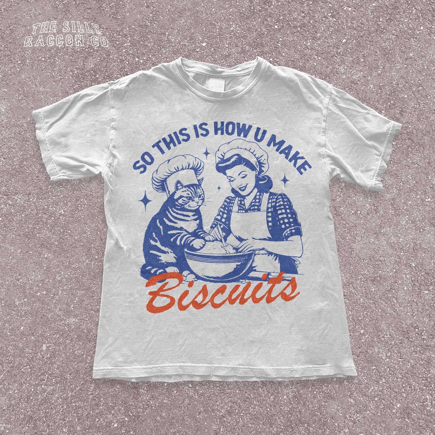 Funny cat t-shirt for men and women featuring a vintage-style illustration of a woman and a cat "making biscuits" together in a mixing bowl. The cat wears a chef hat, humorously mimicking the kneading behavior cats are known for. Retro colors and design give it a nostalgic feel. Great for cat lovers, pet parents, and fans of funny animal shirts. Makes a perfect gift for cat moms, dads, or kitchen humor enthusiasts.