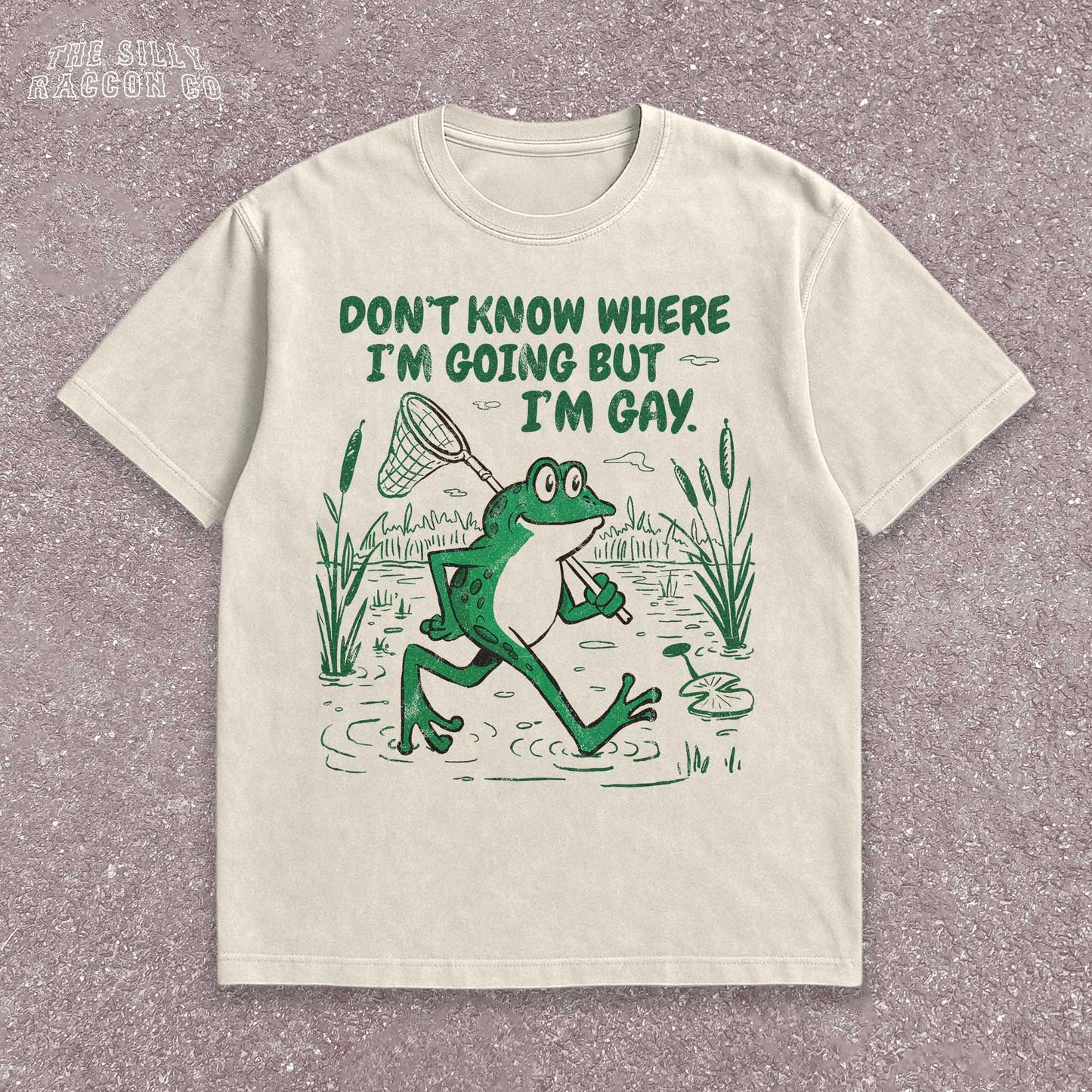 Funny Gay Frog Shirt for men and women featuring a green cartoon frog walking through a marsh carrying a butterfly net over its shoulder. Above the frog, the text reads "DON'T KNOW WHERE I'M GOING BUT I'M GAY" in bold green font. The illustration has a vintage, slightly distressed graphic tee style. This unisex LGBTQ pride t-shirt is a humorous gift for gay friends, perfect for Pride Month or as a coming out gift.
