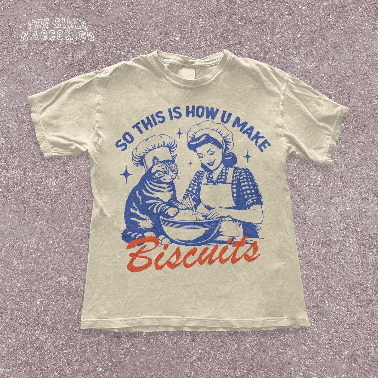 Funny cat t-shirt for men and women featuring a vintage-style illustration of a woman and a cat "making biscuits" together in a mixing bowl. The cat wears a chef hat, humorously mimicking the kneading behavior cats are known for. Retro colors and design give it a nostalgic feel. Great for cat lovers, pet parents, and fans of funny animal shirts. Makes a perfect gift for cat moms, dads, or kitchen humor enthusiasts.