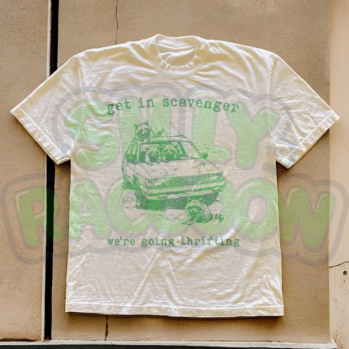 Get In Scavenger We're Going Thrifting" funny raccoon t-shirt for men and women. Vintage-style with a green graphic design of four silly raccoons in a station wagon. Perfect for thrifting lovers. Retro, humorous, unisex tee.