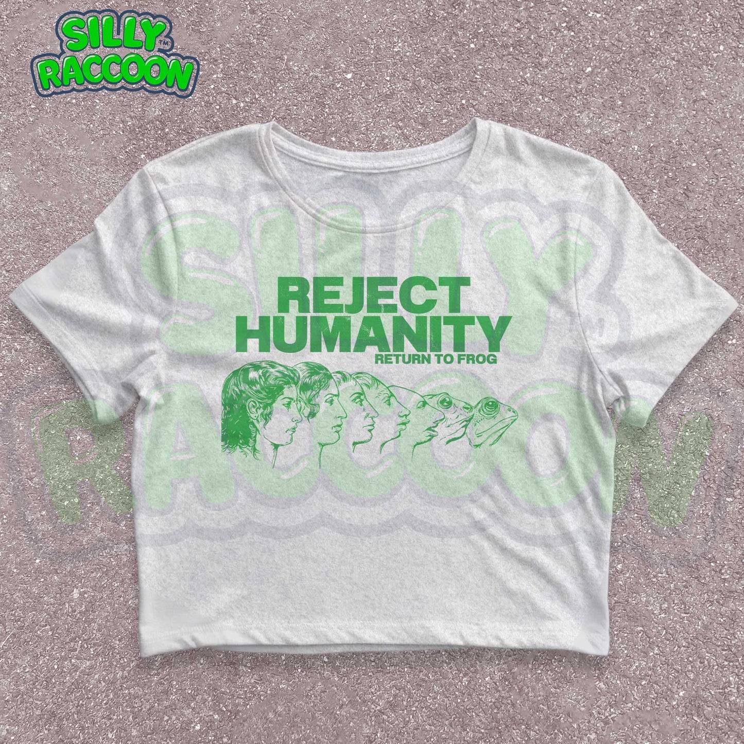 Young woman wearing a white Y2K baby tee, perfect for Gen Z fashion lovers and teens into alt clothing. The shirt features a green graphic print with the text "REJECT HUMANITY RETURN TO FROG" and an illustration showing human faces morphing into frogs. This funny meme shirt taps into internet culture and weirdcore aesthetic. It's a great sarcastic gift for anti-social friends or any frog lover. Ideal casual wear top, this graphic tee suits everyday outfits or alternative style look