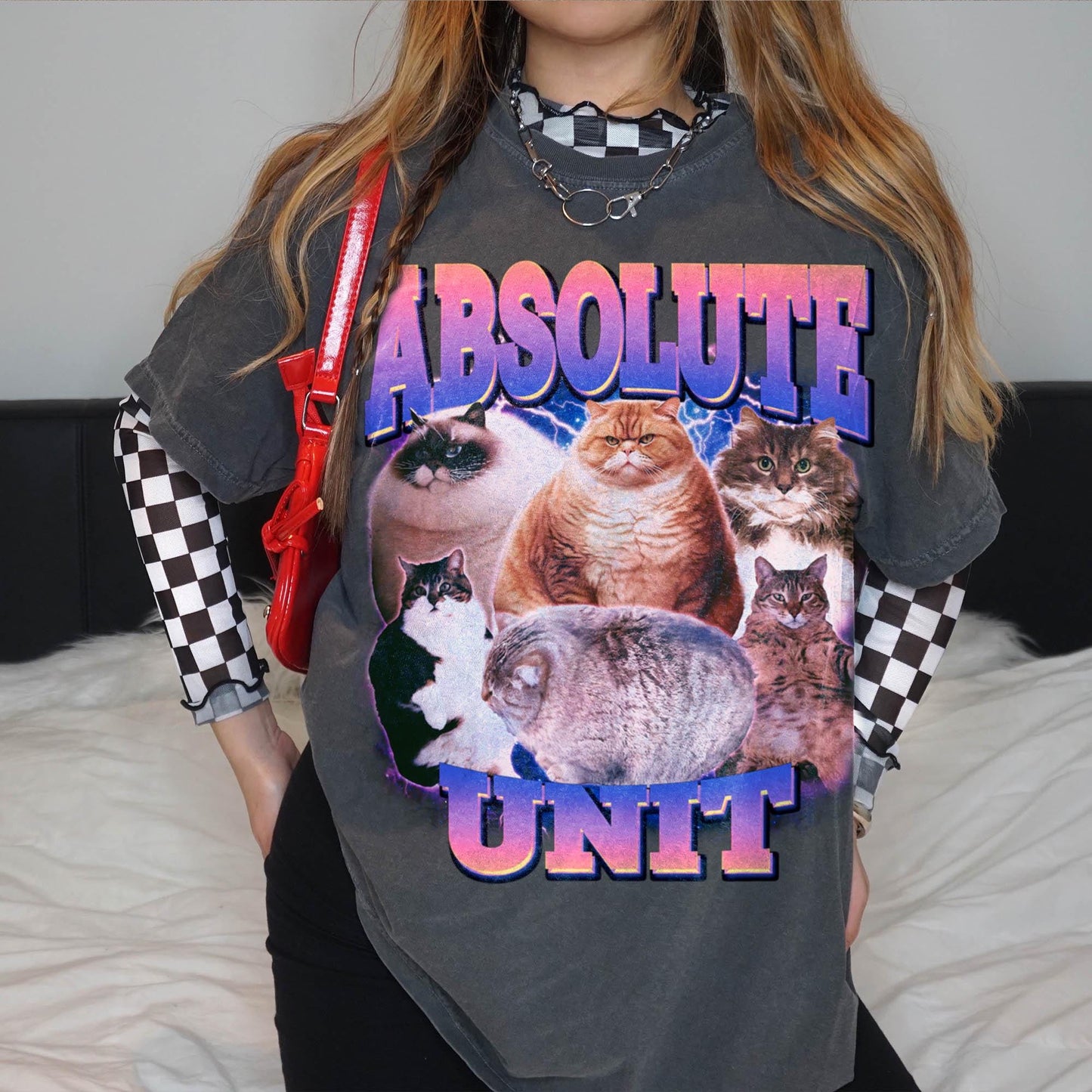 A person wearing a gray t-shirt with a graphic design featuring a group of cats.