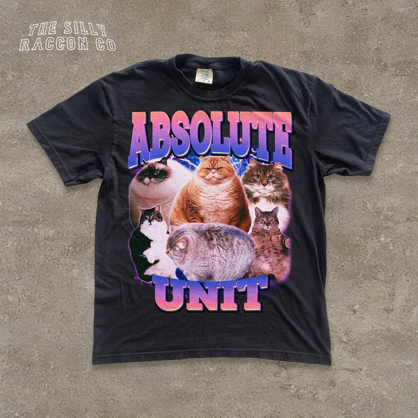 The image is a black t-shirt with a graphic design featuring a group of cats, including a large orange cat and several smaller cats, all sitting together.