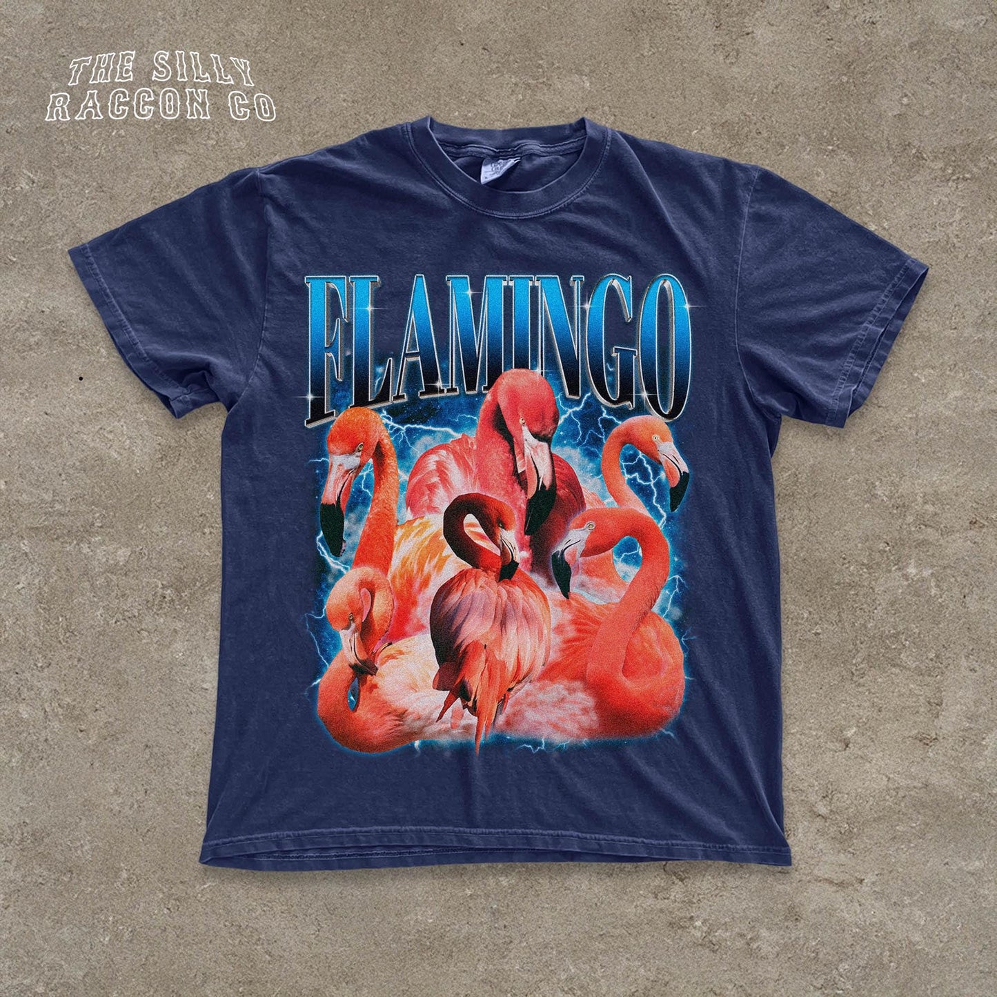A navy blue t-shirt with a graphic design featuring a group of flamingos against a stormy background.