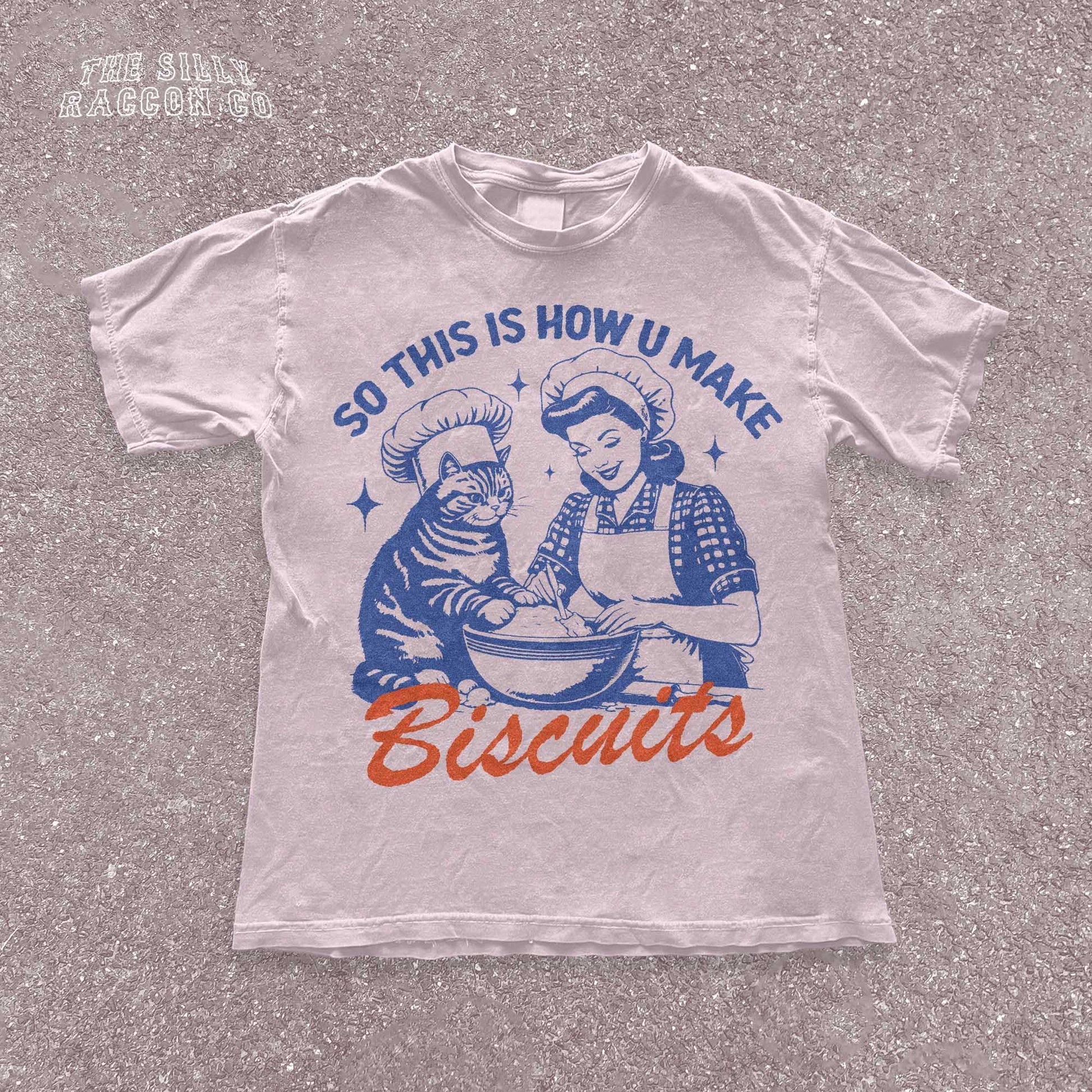 Funny cat t-shirt for men and women featuring a vintage-style illustration of a woman and a cat &quot;making biscuits&quot; together in a mixing bowl. The cat wears a chef hat, humorously mimicking the kneading behavior cats are known for. Retro colors and design give it a nostalgic feel. Great for cat lovers, pet parents, and fans of funny animal shirts. Makes a perfect gift for cat moms, dads, or kitchen humor enthusiasts.