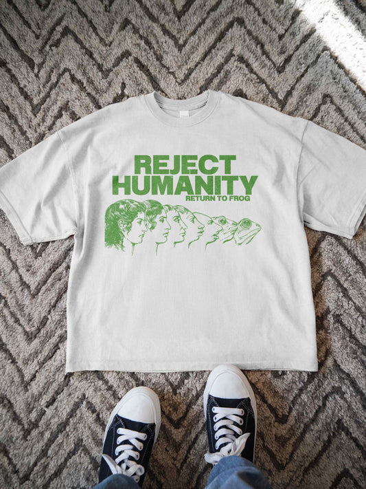 Unisex t-shirt for Gen Z featuring the text &quot;Reject Humanity Return to Frog&quot; in green with an illustrated human-to-frog evolution graphic. Perfect for fans of meme humor, absurdist internet culture, and ironic fashion. Retro Y2K style with soft fabric feel. Great gift idea for frog lovers, internet meme fans, or anyone into weird aesthetics and frogcore vibes.