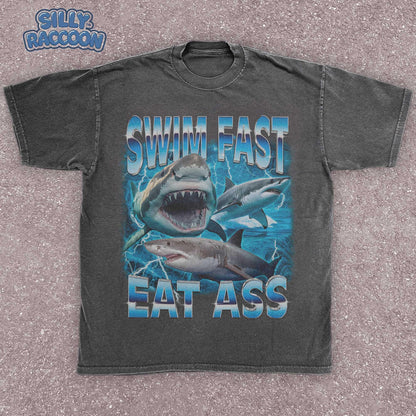 Funny adult humor graphic tee featuring three fierce sharks swimming aggressively with the edgy phrase &quot;Swim Fast Eat Ass.&quot; Vibrant vintage-style design with bold blue letters and ocean wave graphics. Perfect meme culture shirt for young adults, shark lovers, sarcastic friends, or edgy trendsetters. Ideal casual tee for Shark Week, beach trips, parties, or humorous gifts. Provocative yet playful, this shirt makes a bold style statement.