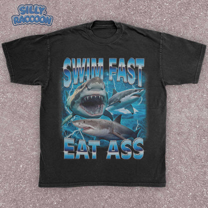 Funny adult humor graphic tee featuring three fierce sharks swimming aggressively with the edgy phrase &quot;Swim Fast Eat Ass.&quot; Vibrant vintage-style design with bold blue letters and ocean wave graphics. Perfect meme culture shirt for young adults, shark lovers, sarcastic friends, or edgy trendsetters. Ideal casual tee for Shark Week, beach trips, parties, or humorous gifts. Provocative yet playful, this shirt makes a bold style statement.
