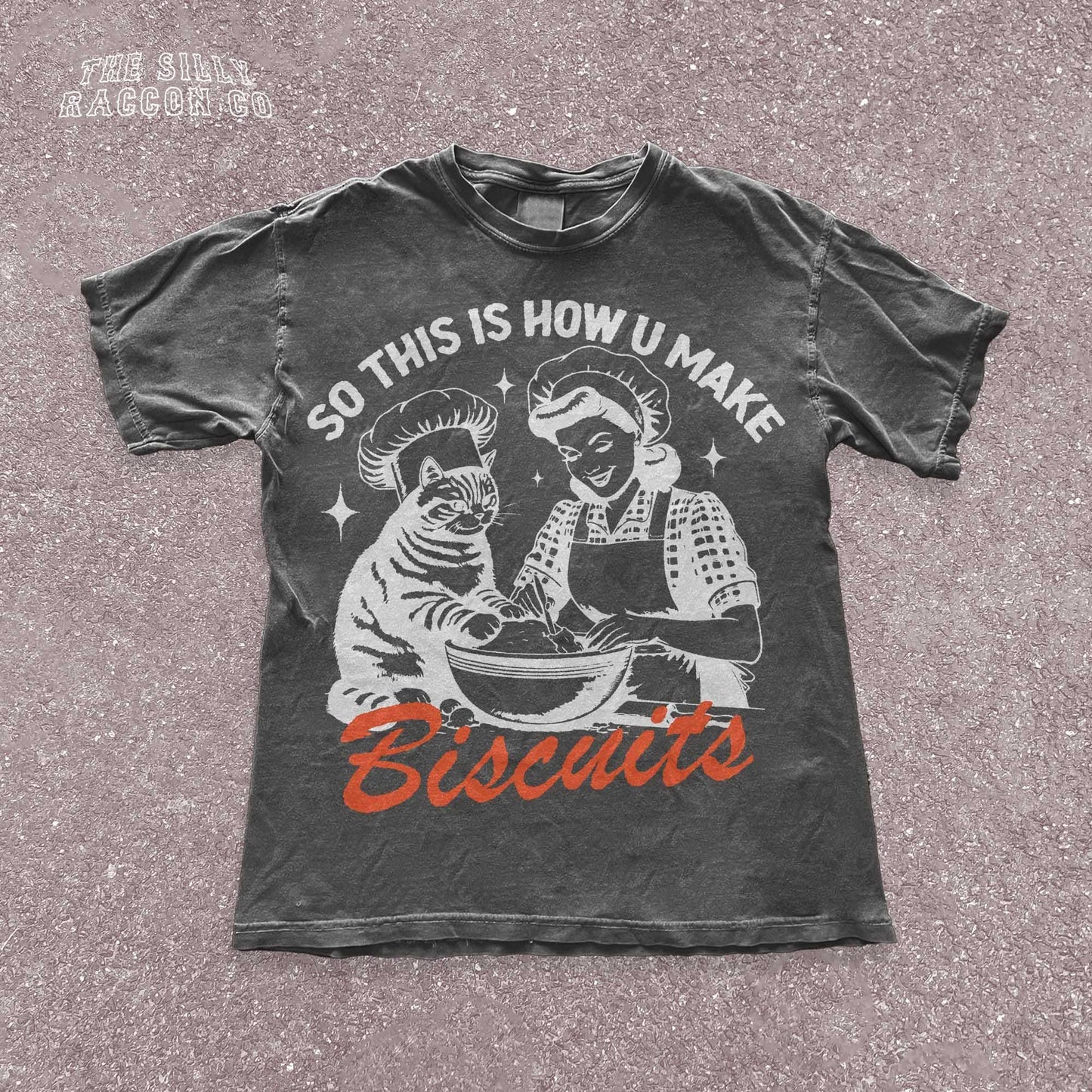 Funny cat t-shirt for men and women featuring a vintage-style illustration of a woman and a cat &quot;making biscuits&quot; together in a mixing bowl. The cat wears a chef hat, humorously mimicking the kneading behavior cats are known for. Retro colors and design give it a nostalgic feel. Great for cat lovers, pet parents, and fans of funny animal shirts. Makes a perfect gift for cat moms, dads, or kitchen humor enthusiasts.