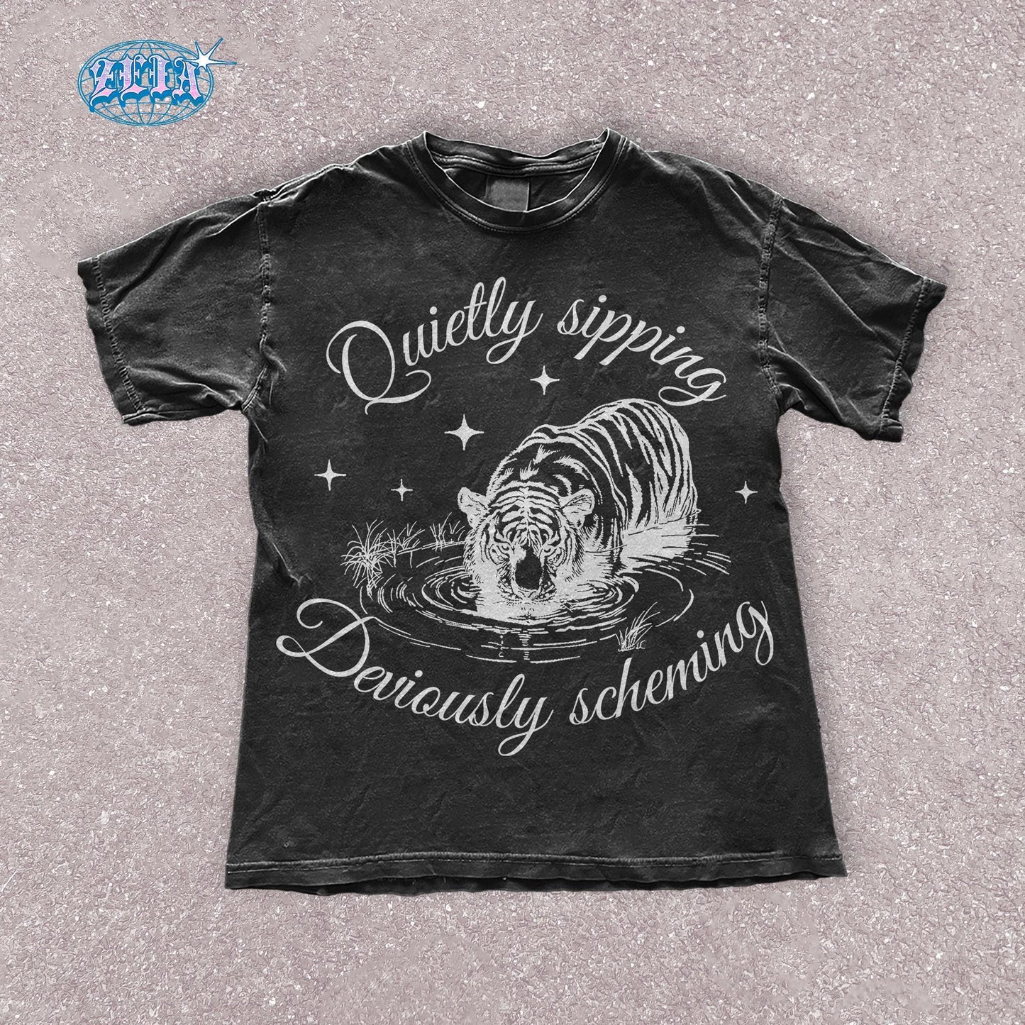 A black t-shirt featuring a detailed black graphic of a tiger quietly sipping water with the text Quietly sipping, deviously scheming elegantly curved above and below the tiger.