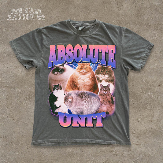 The image is a t-shirt design featuring a collage of various cats, including a large cat and several smaller cats, all sitting together. The text on the t-shirt reads &quot;ABSOLUTE UNIT&quot;.