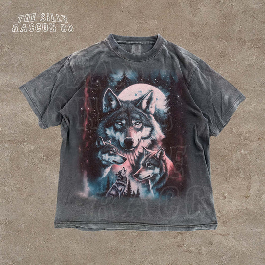 A t-shirt with a graphic design depicting a pack of wolves against a night sky background.